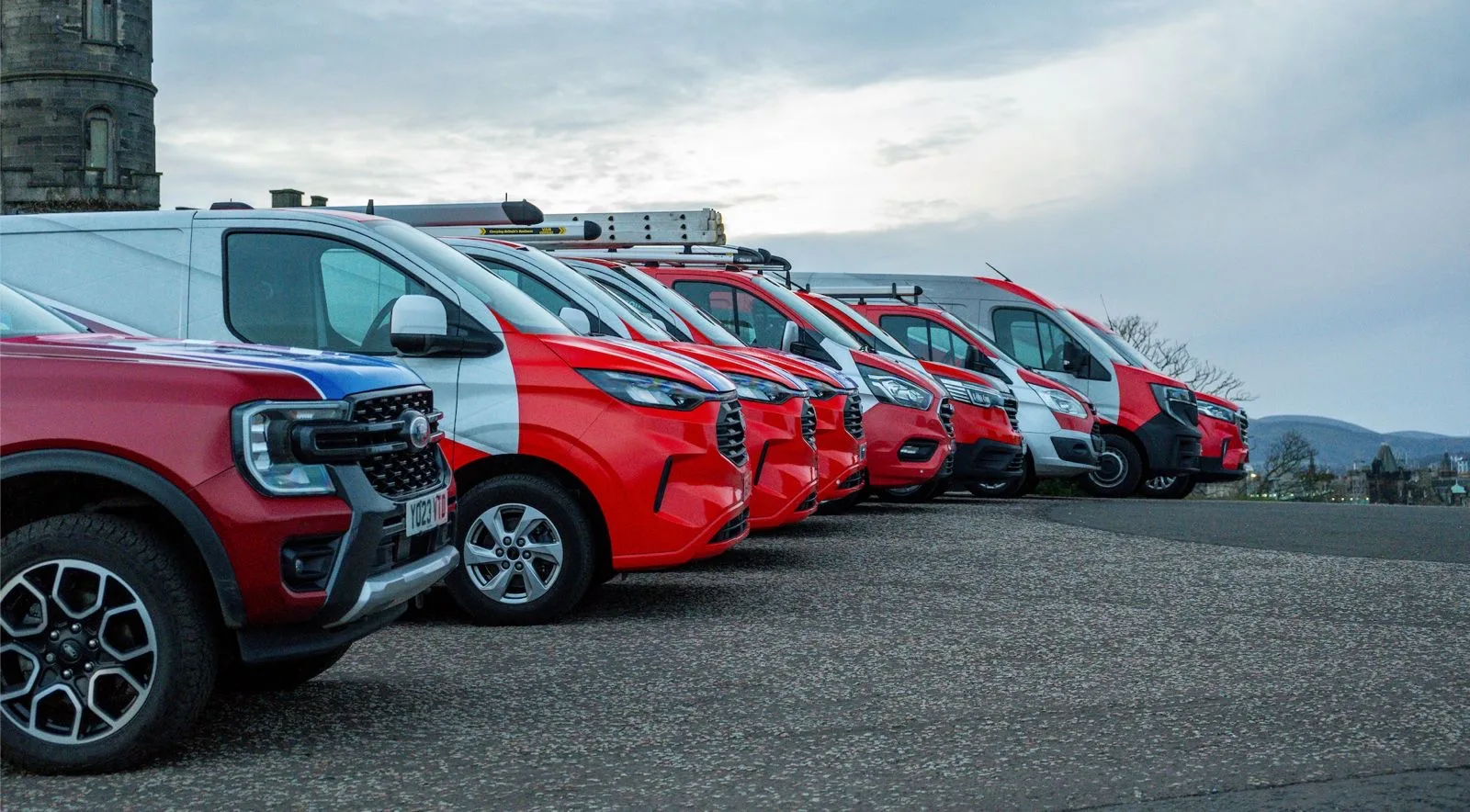 The SD Plumbing & Heating fleet today: eight red and white liveried vans and a pickup lined up on Calton Hill in Edinburgh